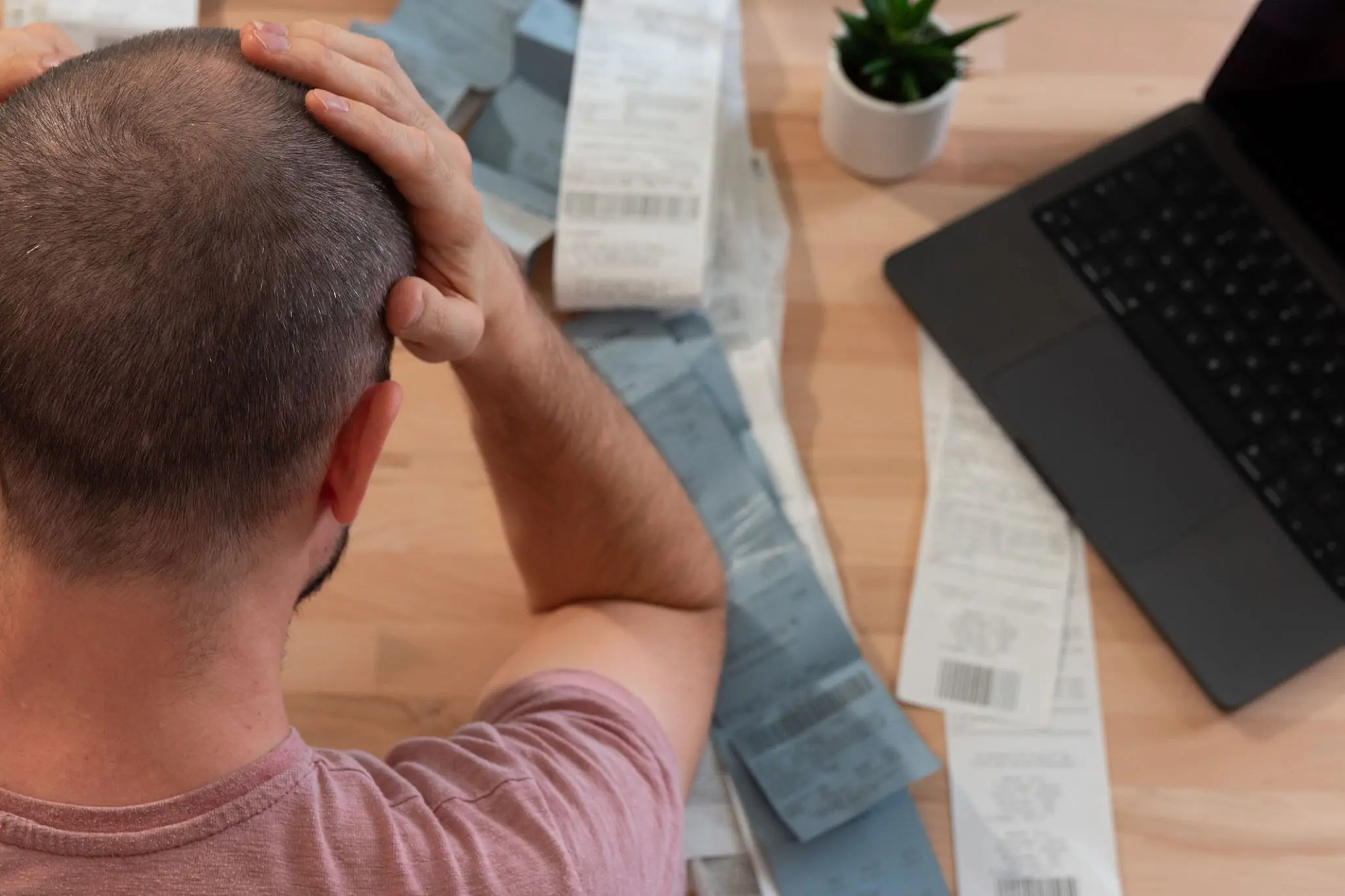 An exhausted person looking at bills on a table showing how financial stress causes burnout.